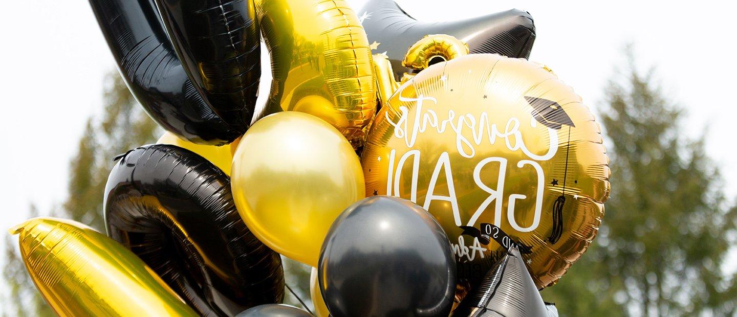 A bundle of gold and black balloons of different shapes and sizes.